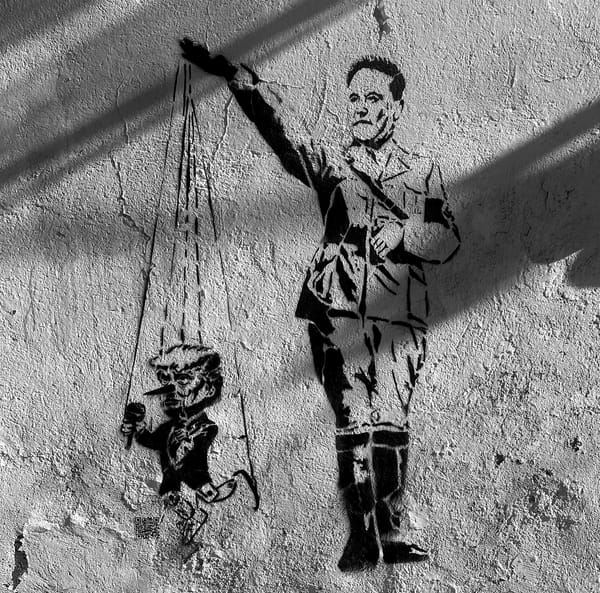 street art stencil by Yescka of Elon Musk in Nazi uniform using Nazi salute hand to puppeteer mini Donald Trump