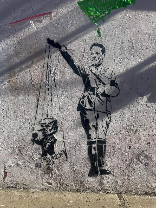 street art stencil by Yescka of Elon Musk in Nazi uniform using Nazi salute hand to puppeteer mini Donald Trump